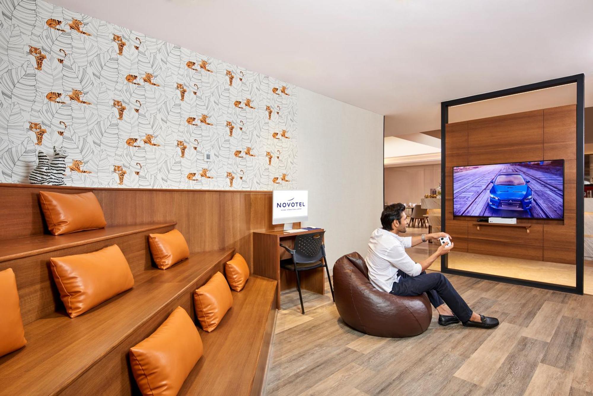 Novotel Mumbai International Airport Esterno foto A man playing a video game at the lounge